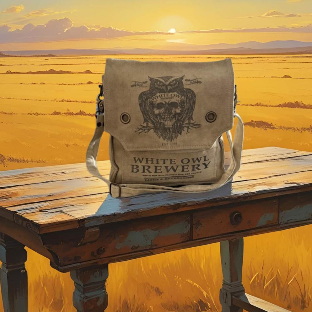 White Owl Brewery bag on a wooden table with a sunset over a field in the background