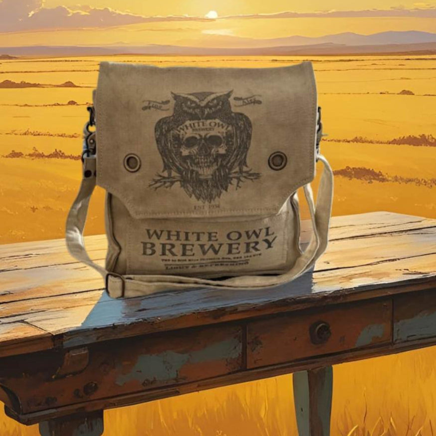 White Owl Brewery bag on a wooden table with a sunset over a field in the background