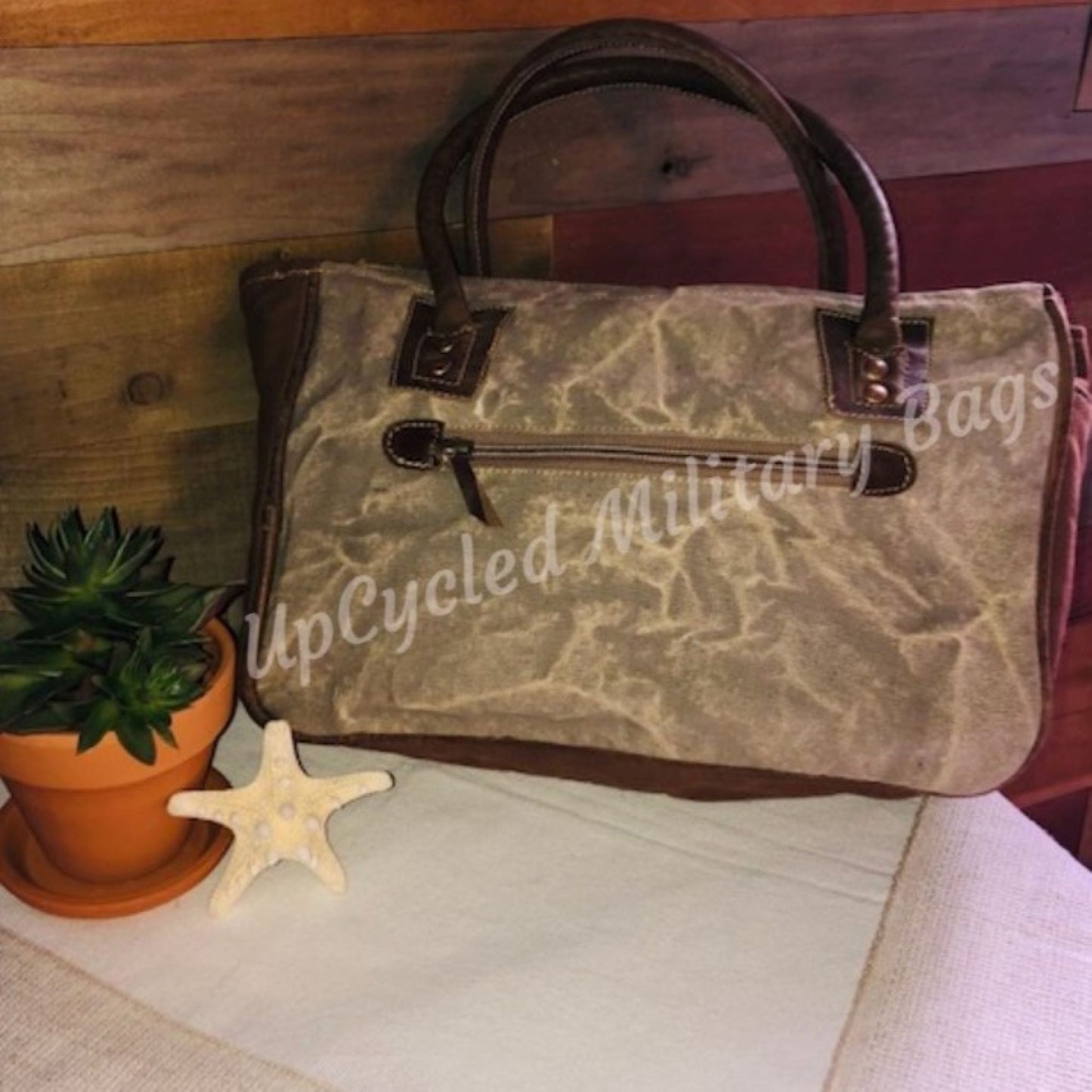 The UpCycled Adventure Tote is made from repurposed military tent and tarp canvas. Along with an image of Angel Wings the bag says: And So the Adventure Begins. This purse is strong and sturdy. It is ready to go on your next adventure but durable enough to make every day an adventure. Perfect Purse / Handbag but also large enough to take as a small travel tote. Dimensions are 13" x 9" x 4". Features: Antique Brass Accents, Top Zippered Closure