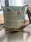 A recycled military canvas crossbody bag in muted green with a brown leather strap and metal hardware.