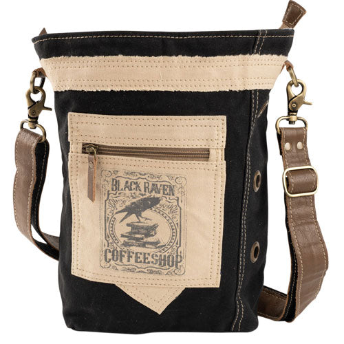 Black and beige crossbody bag with a black raven sitting on a stack of book and the text coffee shop under it. 