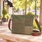 A recycled military canvas crossbody bag in muted green with a brown leather strap and metal hardware.