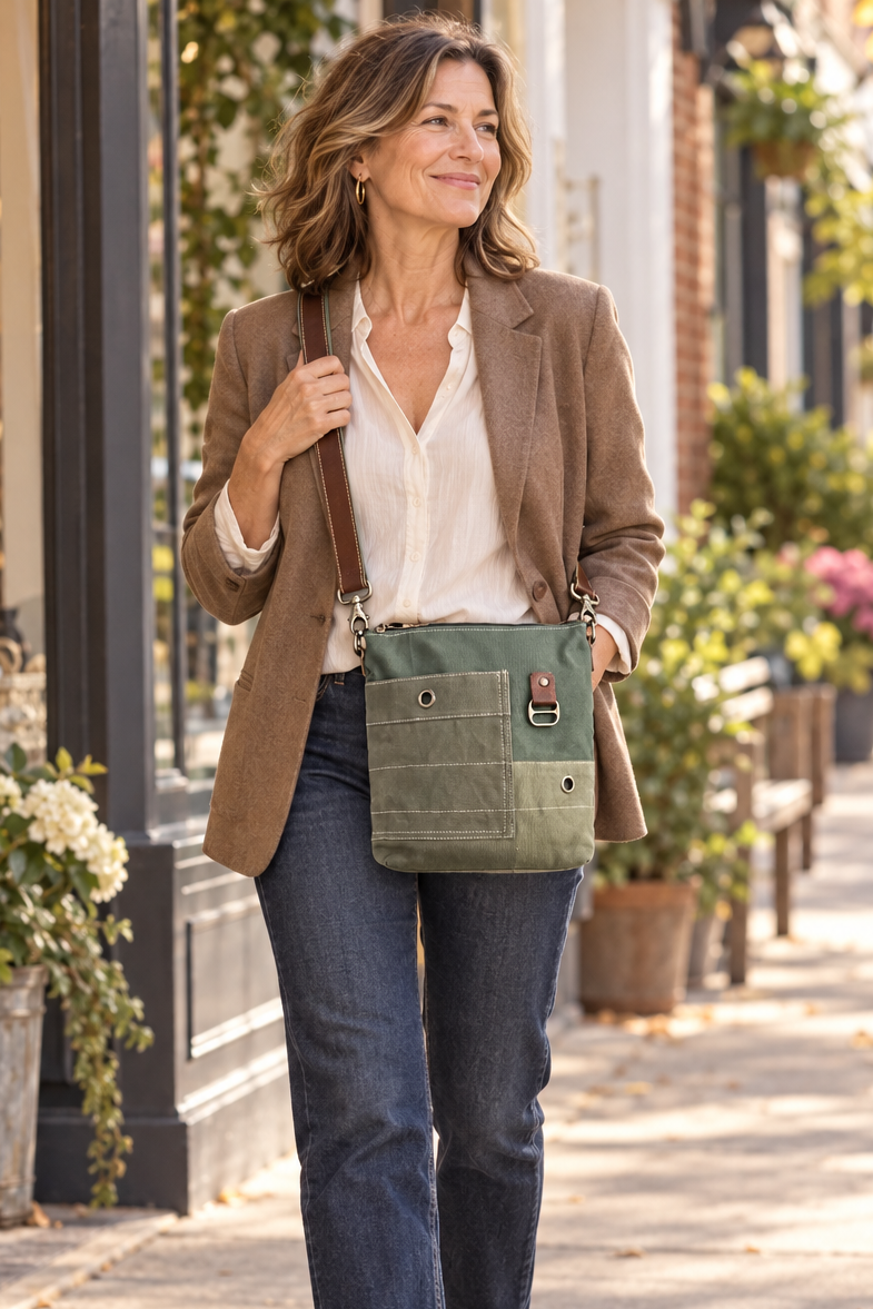 green recycled military canvas crossbody being worn by by a chic woman .