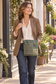 green recycled military canvas crossbody being worn by by a chic woman .