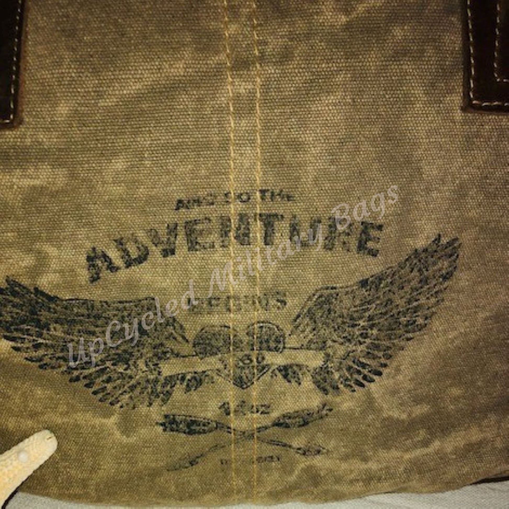 The UpCycled Adventure Tote is made from repurposed military tent and tarp canvas. Along with an image of Angel Wings the bag says: And So the Adventure Begins. This purse is strong and sturdy. It is ready to go on your next adventure but durable enough to make every day an adventure. Perfect Purse / Handbag but also large enough to take as a small travel tote. Dimensions are 13" x 9" x 4". Features: Antique Brass Accents, Top Zippered Closure
