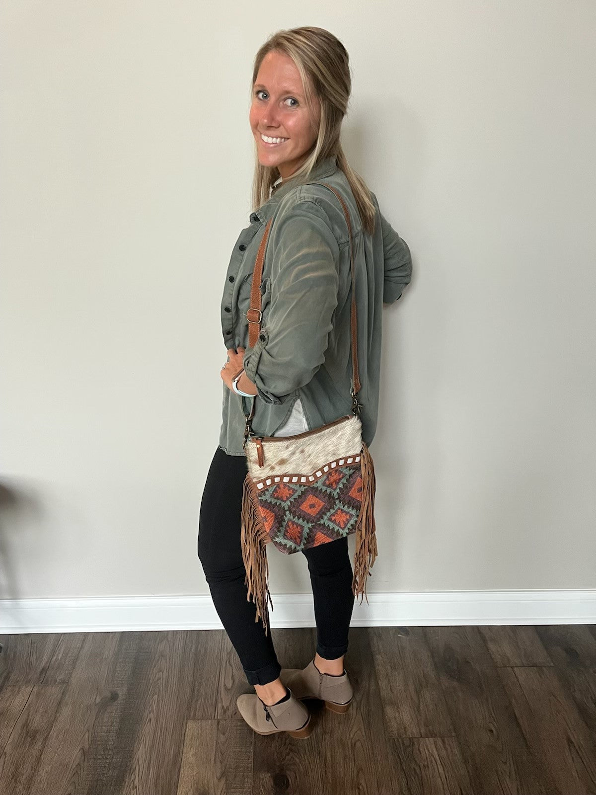 image of a girl wearing our repurposed turquoise tapestry and military canvas crossbody bag with hairon hide and fringe.
