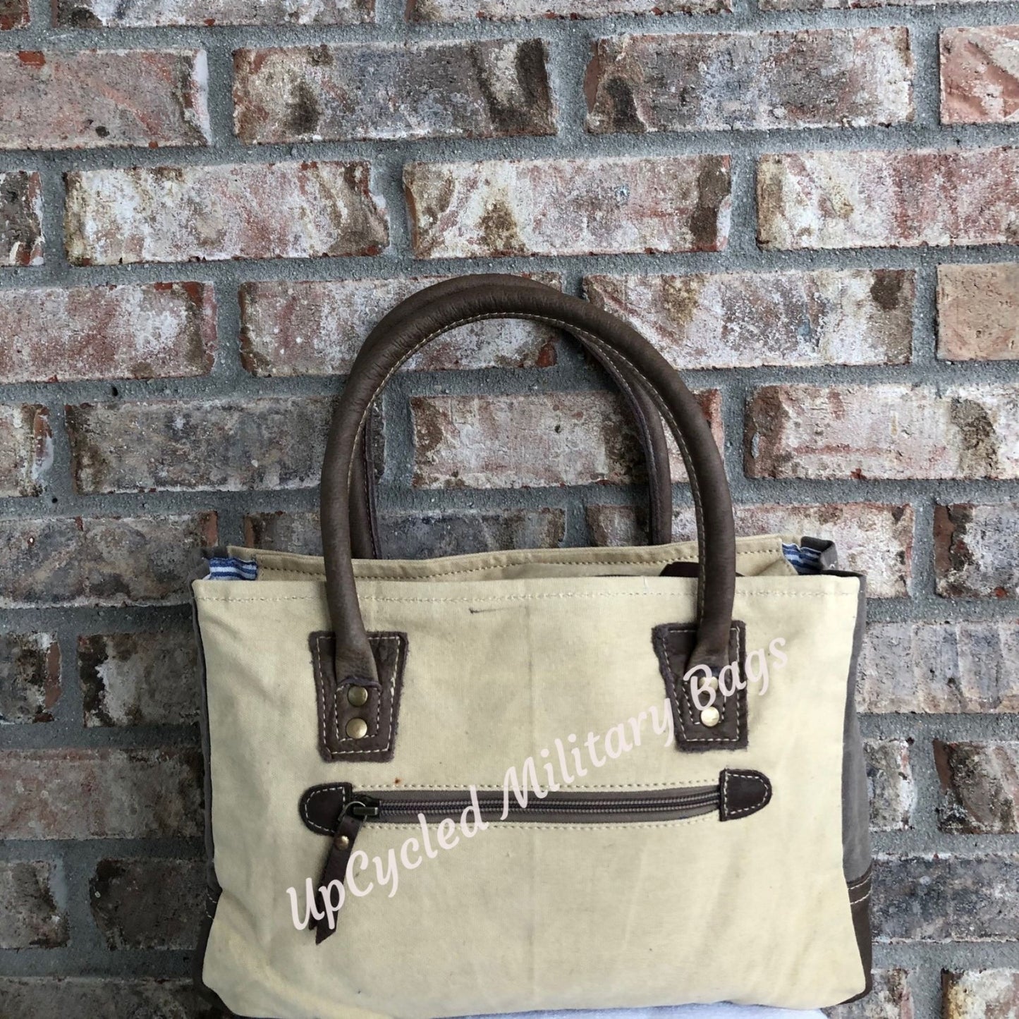 The UpCycled Vintage Buck Shoulder Bag / Tote is made from repurposed military tent and tarp canvas!  This purse gives off a vintage vibe with the Original Vintage Buck on the front.  It provides comfort with padded handles.  It has a zippered back pocket, a zipped inside pocket and is fully lined.